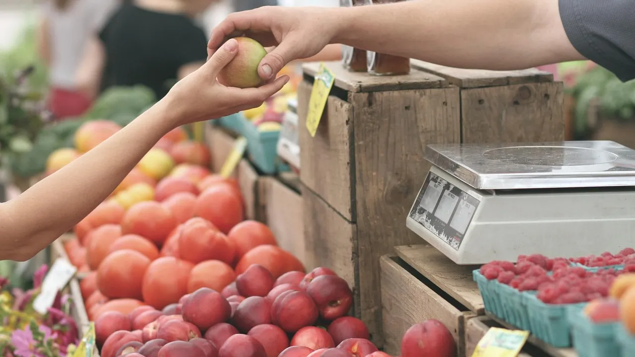 Échange d'un fruit sur un étal de marché, près de la balance