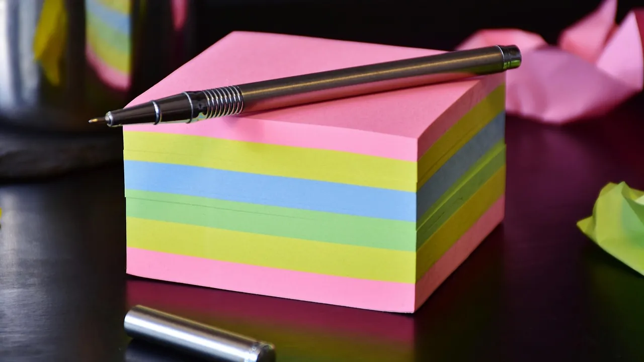 Bloc de papillons adhésifs multicolores et un stylo posé dessus